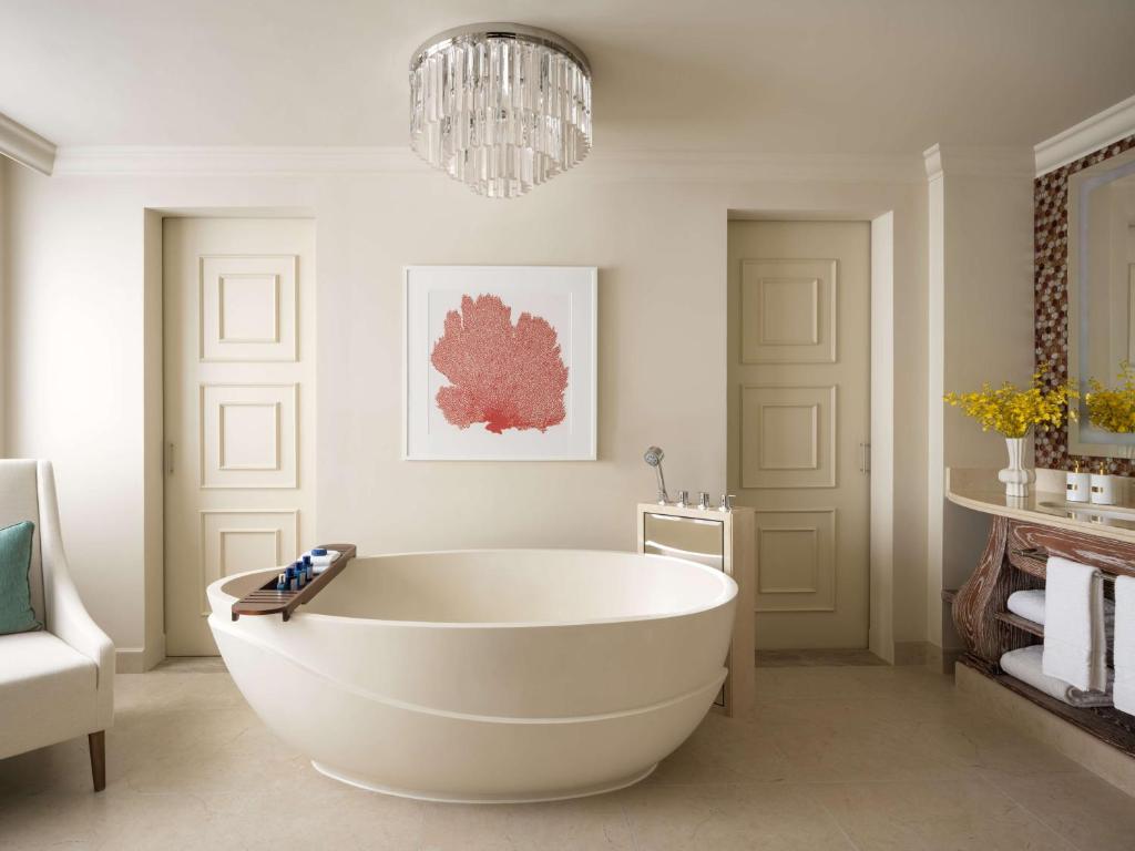 a white bath tub in a bathroom with a chandelier at Atlantis, The Palm in Dubai