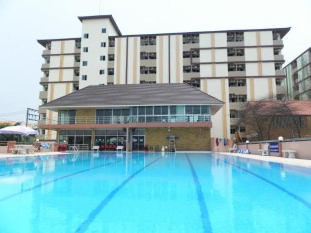 a large swimming pool in front of a large building at One Residence Navanakorn in Pathum Thani