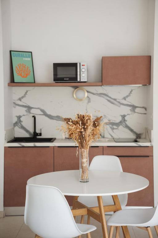 a white table with chairs and a vase with flowers at Hôtel & Résidence San Roccu in Saint-Florent