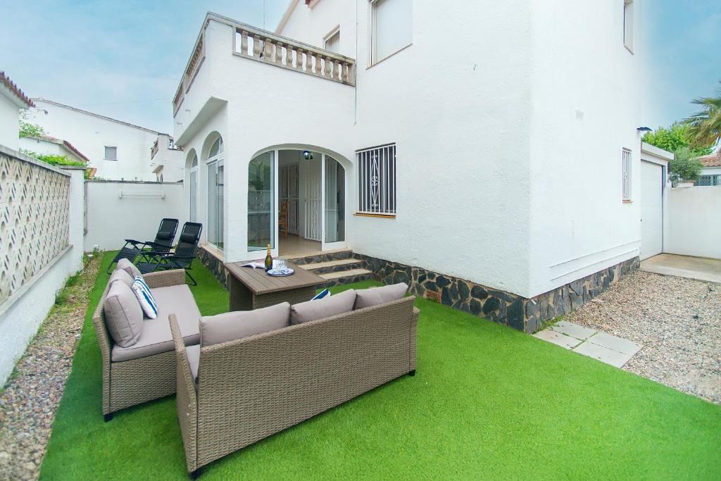 a backyard with green grass and a white house at WELCS CASA 089 EMP cerca del mar in Empuriabrava