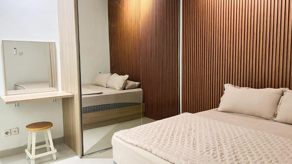 une chambre avec un miroir, un lit et un tabouret dans l'établissement Moona Homestay Jogja, à Gondowulung