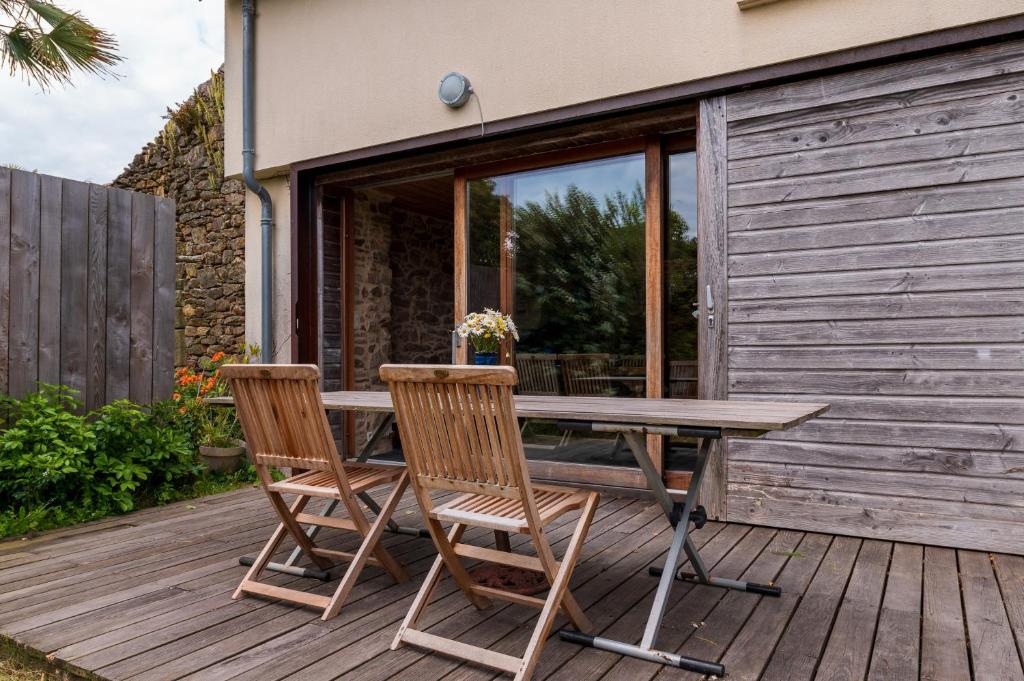 une table en bois et deux chaises sur une terrasse dans l'établissement A la Saline plage à 10min à pied, à Saint-Gildas-de-Rhuys