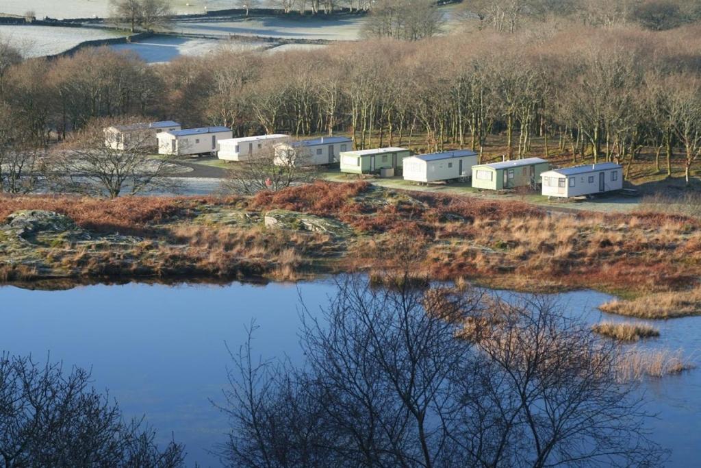 a group of camper trailers on a hill next to a river at Dinas in Llanbedr