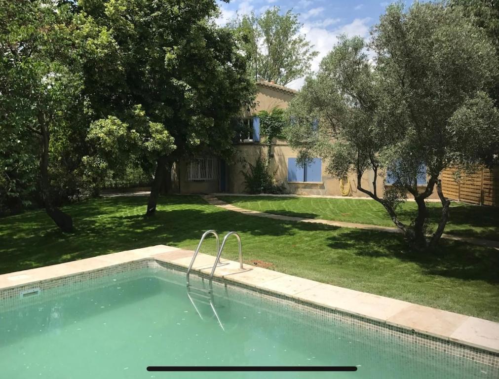 a swimming pool in front of a yard with trees at Ancienne Maison de Campagne in Grans