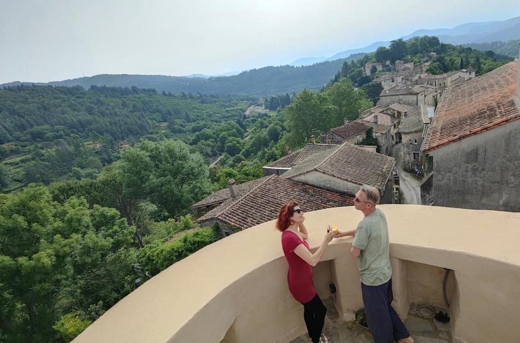 un homme et une femme debout au bord d'un bâtiment dans l'établissement Tour 17e s pour 4, panoramique Cévennes, à Mars