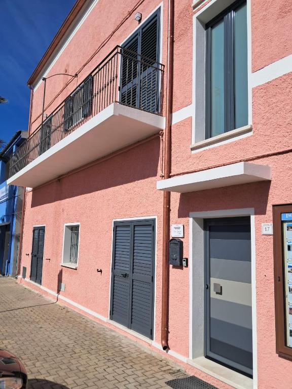 a pink building with a balcony on a street at House Pale Rooms in Palau