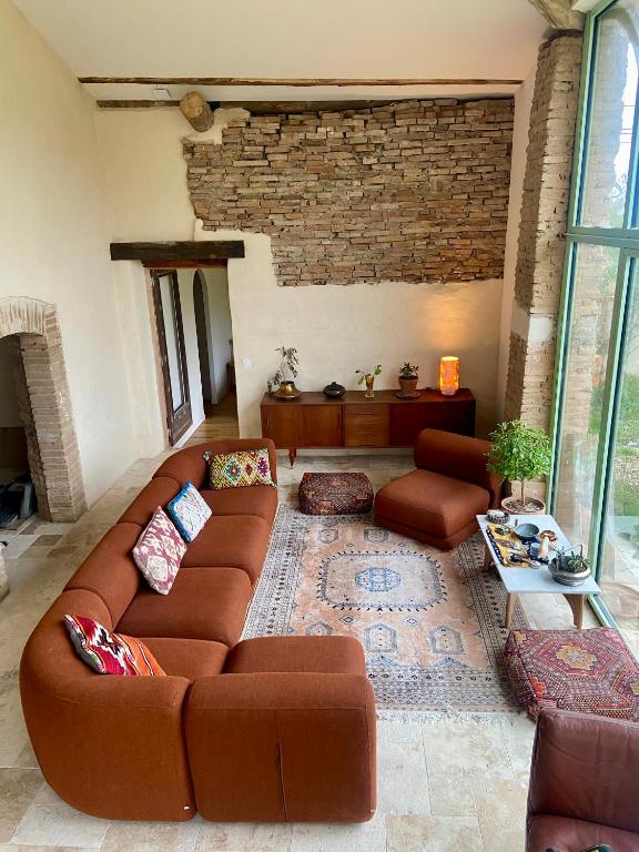 - un salon avec un canapé brun et un mur en briques dans l'établissement Chez Gui & Jisuk T6 Maison Dam Dam Léojac, à Léojac