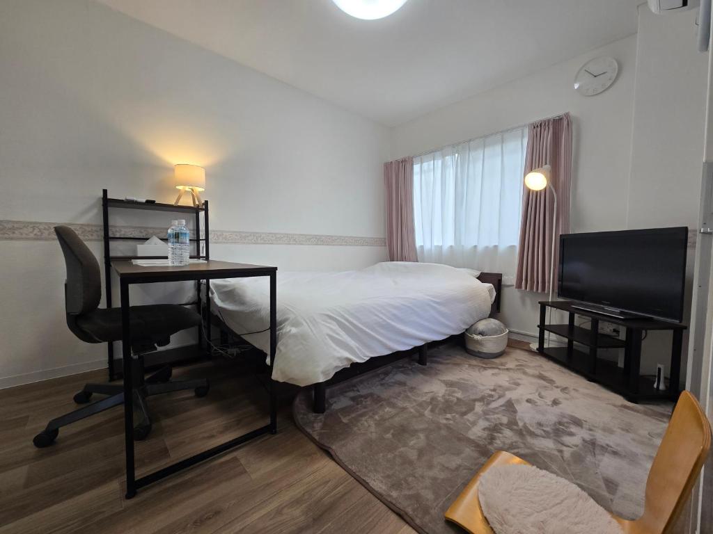 a hotel room with a bed and a desk and a television at SABBATH uzumasa 101 in Kyoto
