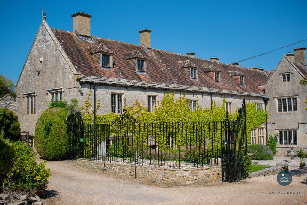 an old stone house with a wrought iron fence at Poxwell Manor West Wing - Exclusive Dorset Retreat in Poxwell