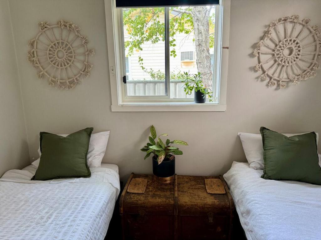 a room with two beds and a window and a table at Indys Place in Bright