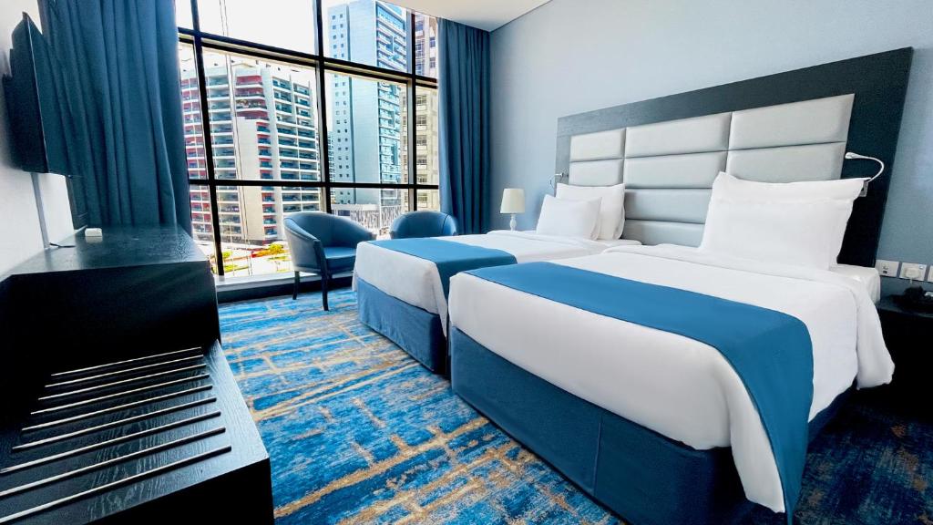 a hotel room with two beds and a large window at Signature 1 Hotel Tecom in Dubai