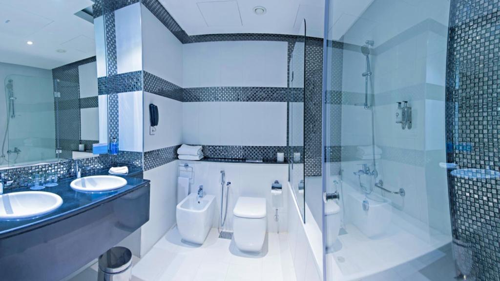 a bathroom with two sinks and two toilets at Signature 1 Hotel Tecom in Dubai