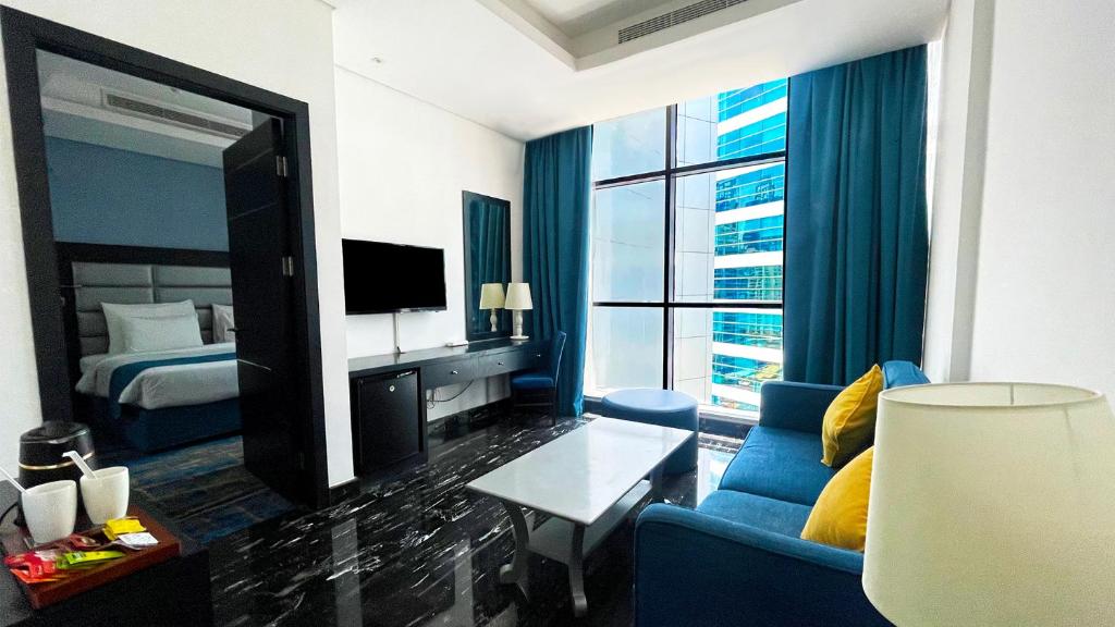 a hotel room with a blue couch and a bedroom at Signature 1 Hotel Tecom in Dubai