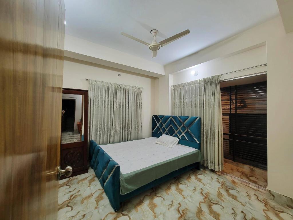 a bedroom with a blue bed and a door at Lovely two bed flats by Dhaka Shahjalal Airport in Dhaka