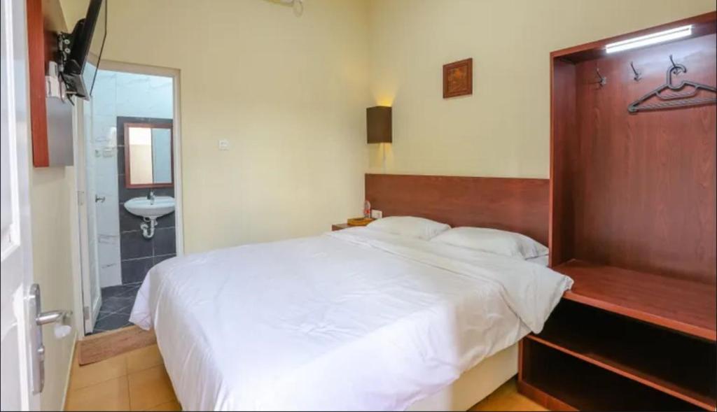 une chambre avec un grand lit blanc et une salle de bain dans l'établissement Comfy Room Yogyakarta BY Hamsa Putih, à Yogyakarta