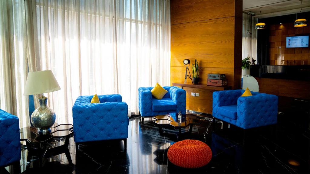 a living room with blue chairs and a table at Signature 1 Hotel Tecom in Dubai