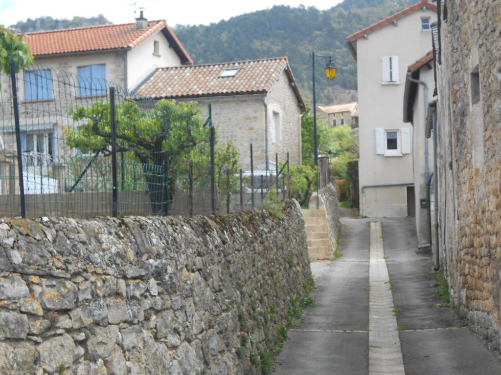 a stone wall next to a street with houses at Gite du plô in La Cresse