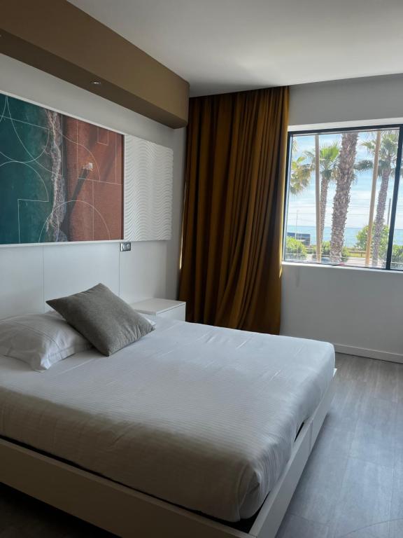 a bedroom with a large bed with a large window at SoBlue Hôtel in Antibes