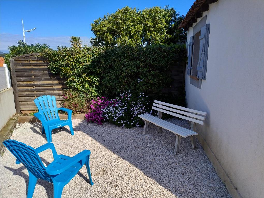 Deux chaises bleues et un banc à côté d'un bâtiment dans l'établissement la plage en face , 2 chambres clim parking, au Pradet