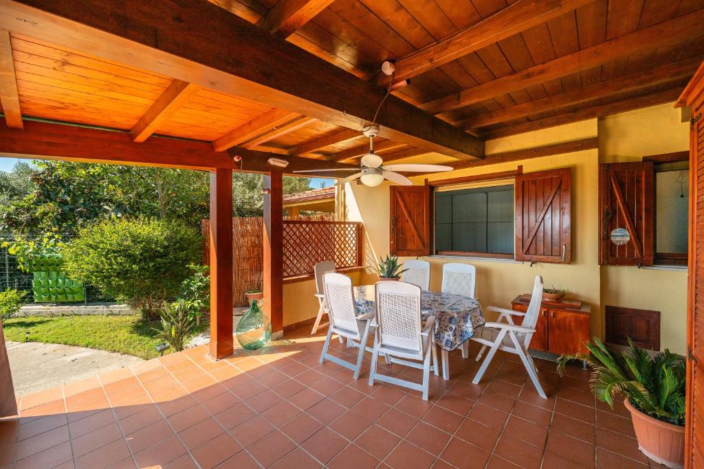 eine Terrasse mit einem Tisch und weißen Stühlen darauf in der Unterkunft Casa vacanza Mar Mediterraneo in Flumini di Quartu