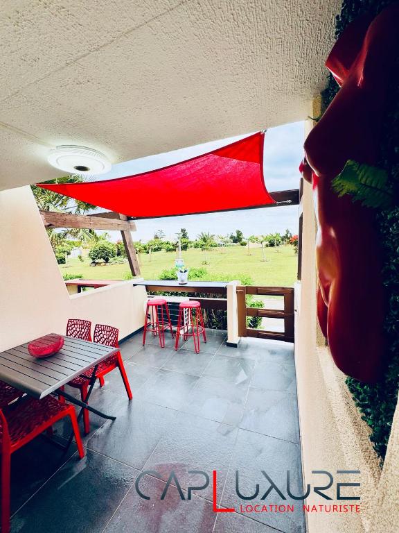 un balcon avec une table, des chaises et un parasol dans l'établissement CAPLUXURE - Port nature 8 - village naturiste Cap d Agde, au Cap d'Agde