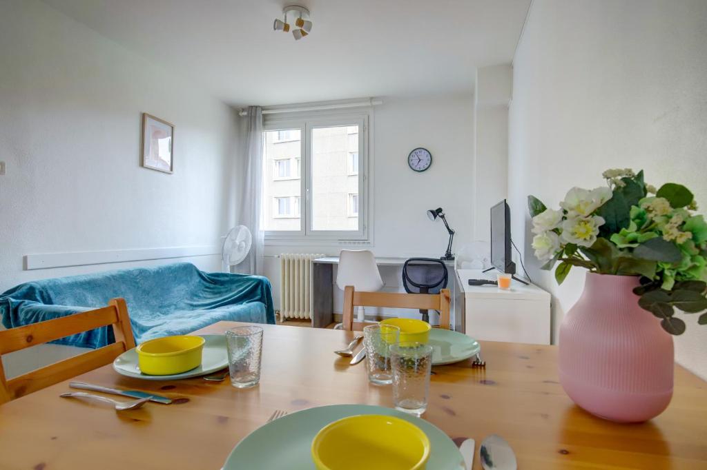 une table de salle à manger avec un vase de fleurs dessus dans l'établissement Le Soleil Levant parking facile, à Toulouse