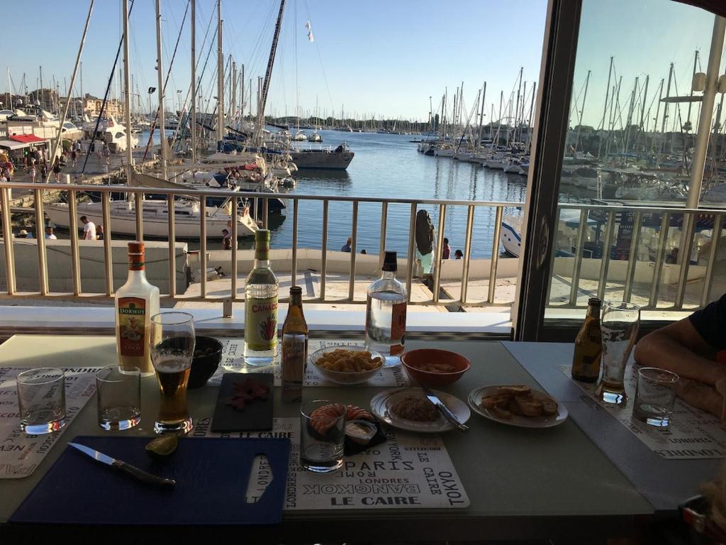 une table avec de la nourriture et des bouteilles de vin et une vue sur un port dans l'établissement Tout confort en première ligne, au Cap d'Agde