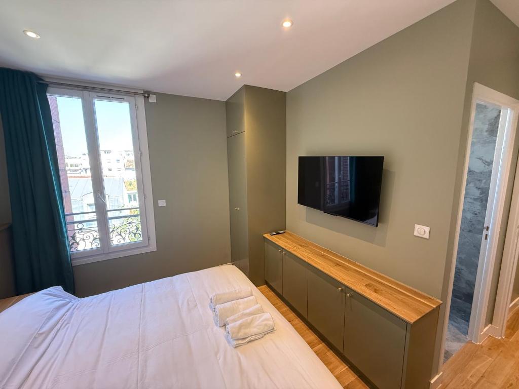a bedroom with a bed and a flat screen tv at Alma Hotel in Courbevoie