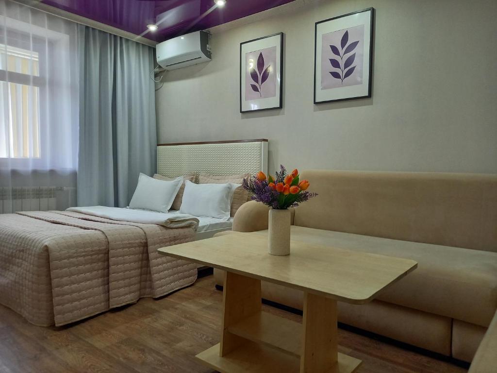 a room with a bed and a table and a couch at Лунная Гавань in Aktobe
