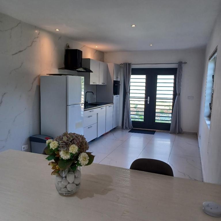 a kitchen with a table with a vase of flowers on it at Flamingo Apartment - Regal Rentals Curacao in Willemstad