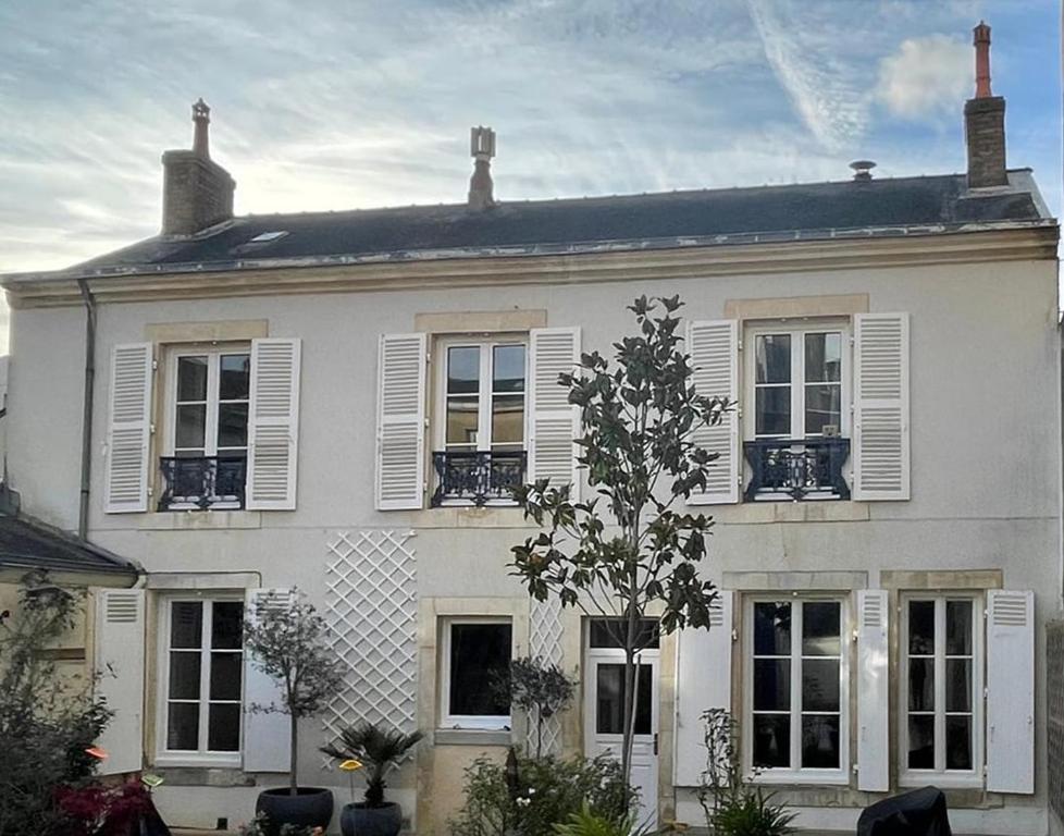 une maison blanche avec des fenêtres à volets blancs et un arbre dans l'établissement Maison indépendante en centre ville, au Mans