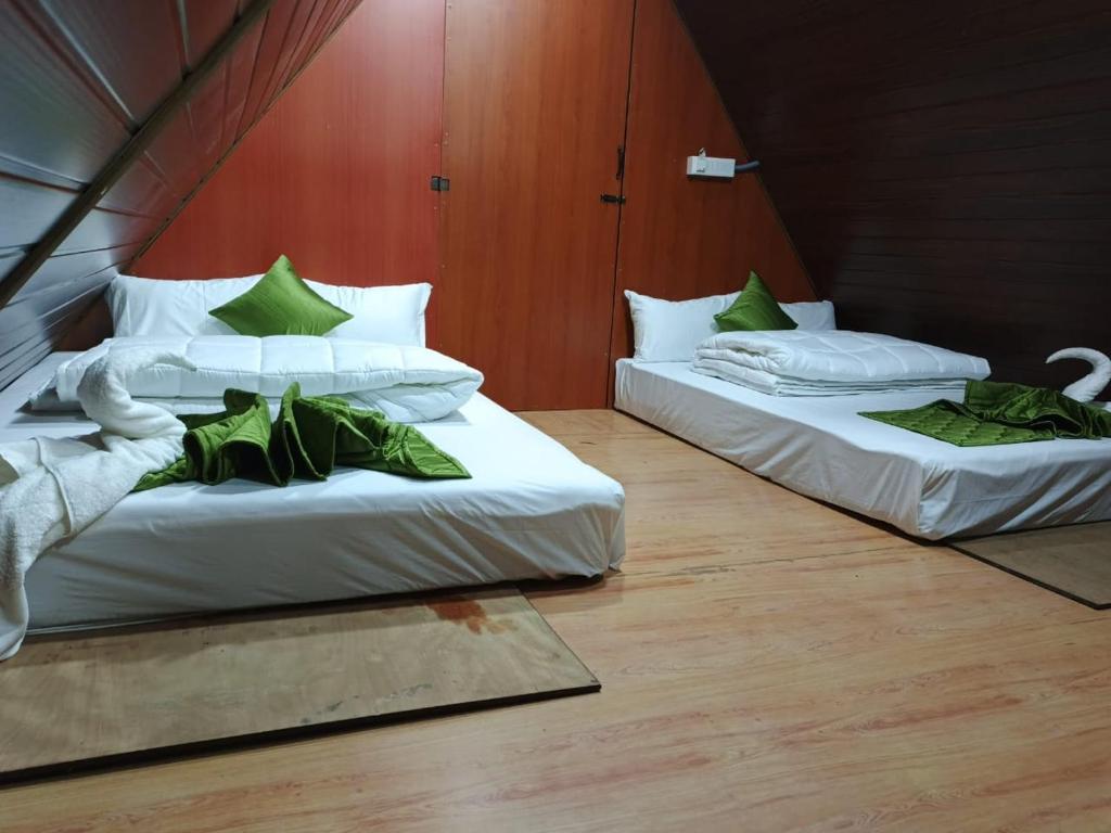 2 letti con lenzuola verdi e bianche in una stanza di Hill Forrest Resort By Sky Inn a Yelagiri