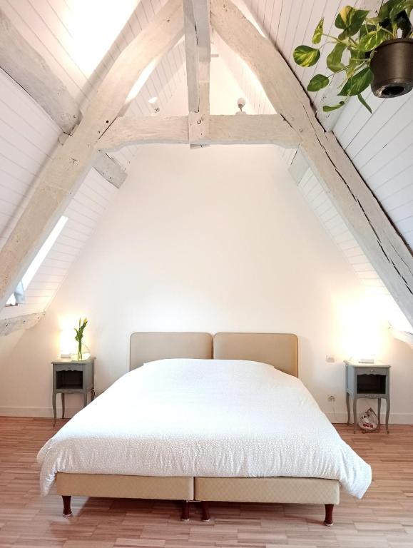 une chambre avec un lit blanc dans un grenier dans l'établissement La maison perchée, à Bayeux