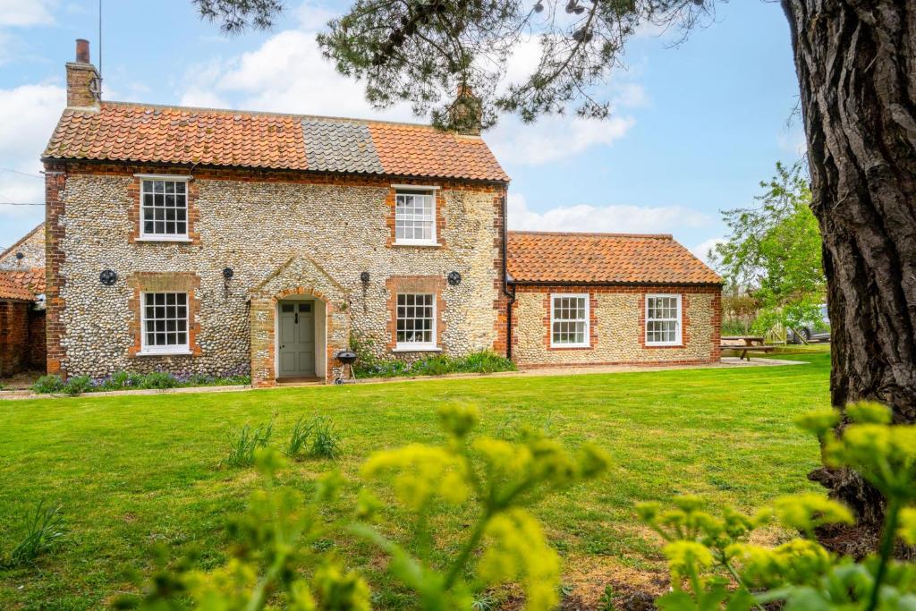 an old brick house with a green yard at Old Posting in Brancaster