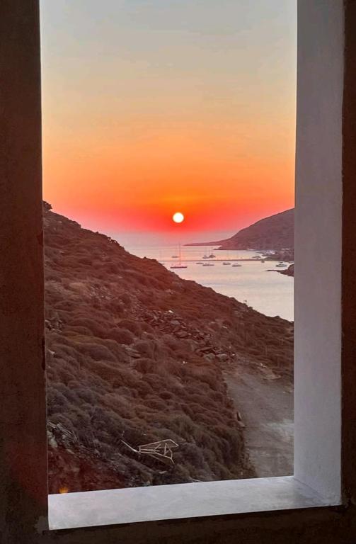 a view of a sunset through a window at Vista del sole Kythnos in Kithnos