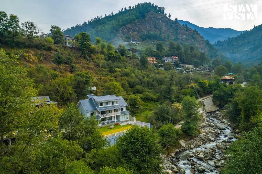 a house on a hill next to a river at StayVista at Riverside Symphony -5BR Villa in Manali with River access in Manāli