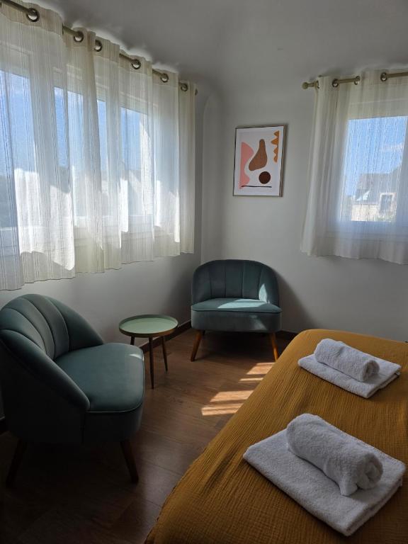 a room with two beds and a chair and window at Brit Hotel des Halles in Concarneau