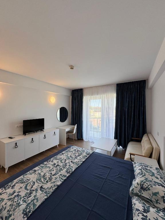 a hotel room with a large bed and a television at Gabriela Blaxy Apartamente in Olimp
