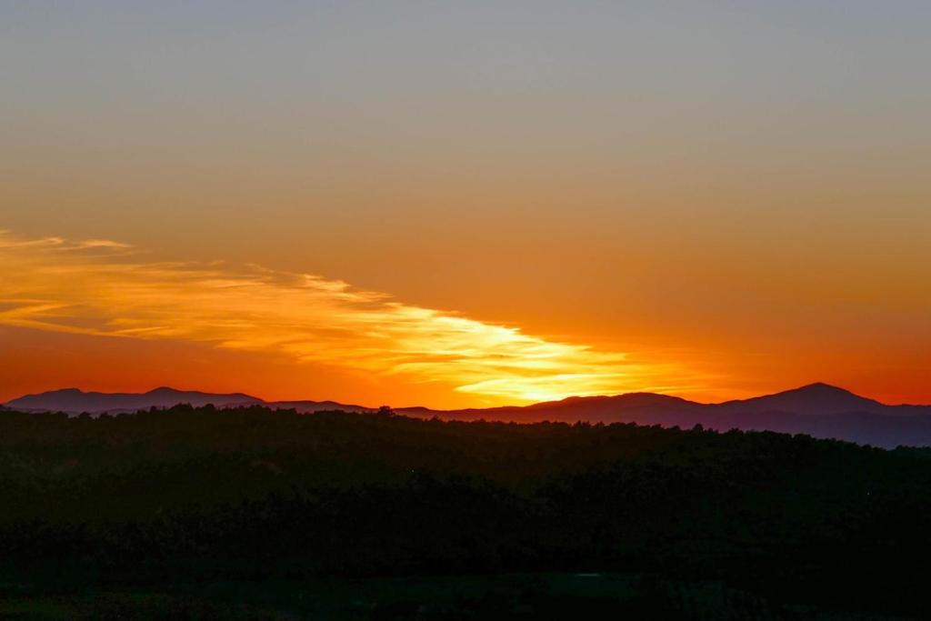 una puesta de sol con montañas en el fondo en Lo ZIO EZIO, en Montepulciano