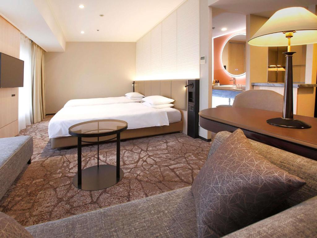una camera d'albergo con un letto e un divano di The Cypress Mercure Hotel Nagoya a Nagoya