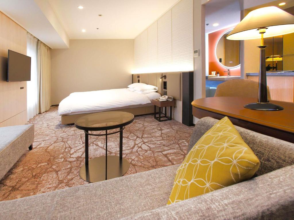 una camera d'albergo con un letto e un divano di The Cypress Mercure Hotel Nagoya a Nagoya