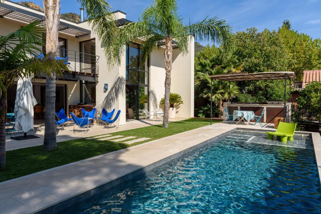 - une piscine dans l'arrière-cour d'une maison avec des palmiers dans l'établissement Laminerve Pramousquier, au Lavandou