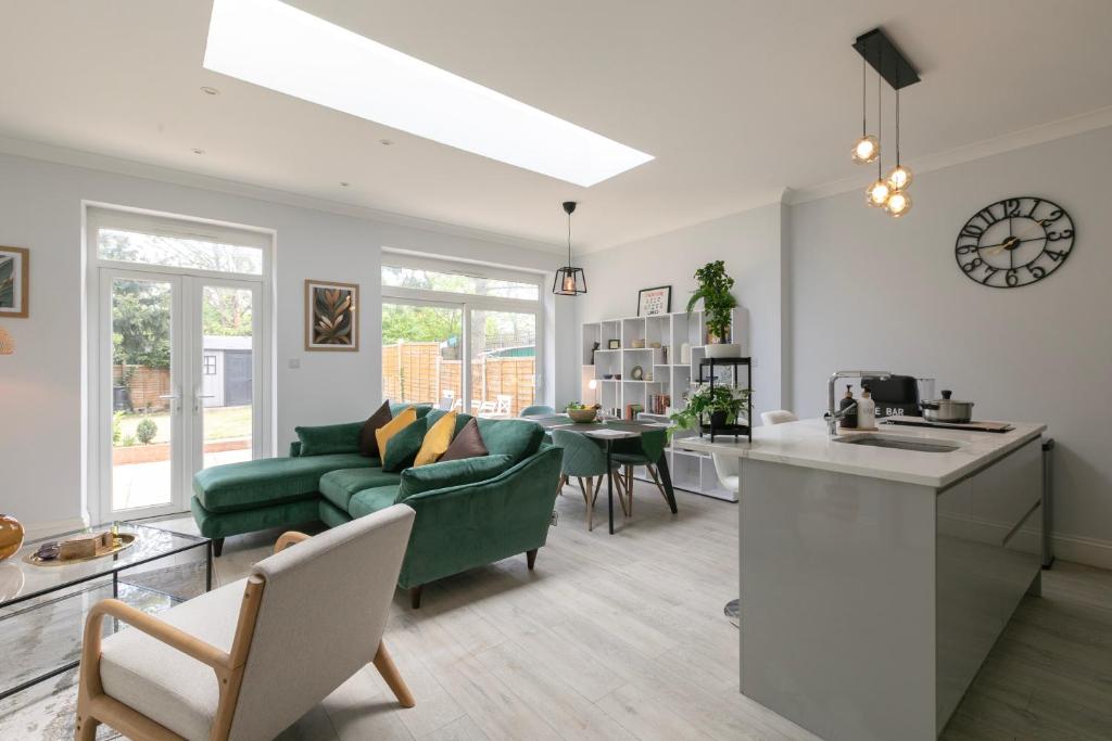 a living room with a green couch and a kitchen at London 5 BR 3 Bathroom Garden Hse Near Metro and Hampstead Heath Sleeps 10 in London