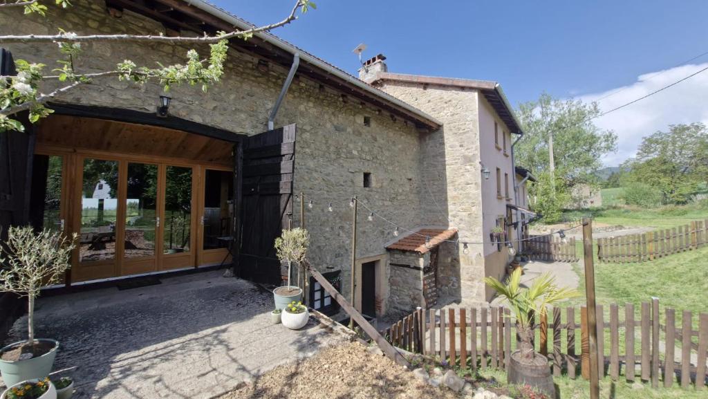 an external view of a stone house with a fence at La Maison Rose in Bertignat