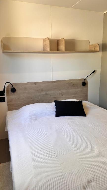 a large white bed with a black pillow on it at Camping Villa Park Zambujeira do Mar in Zambujeira do Mar