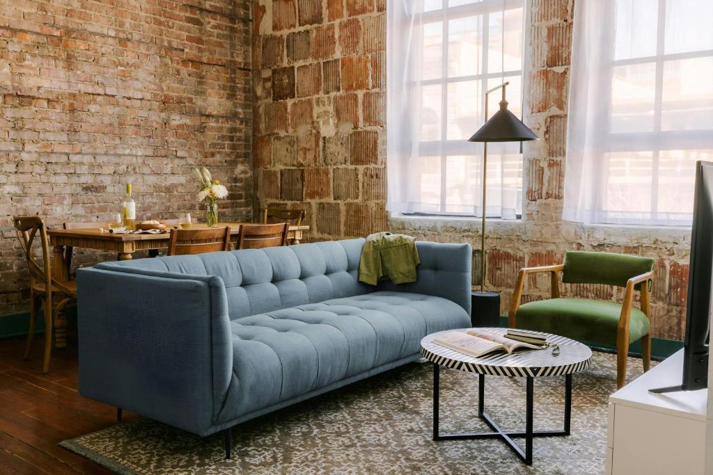 ein Wohnzimmer mit einem blauen Sofa und einer Ziegelwand in der Unterkunft Sonder by Marriott Bonvoy The Schaeffer Apartments French Quarter in New Orleans