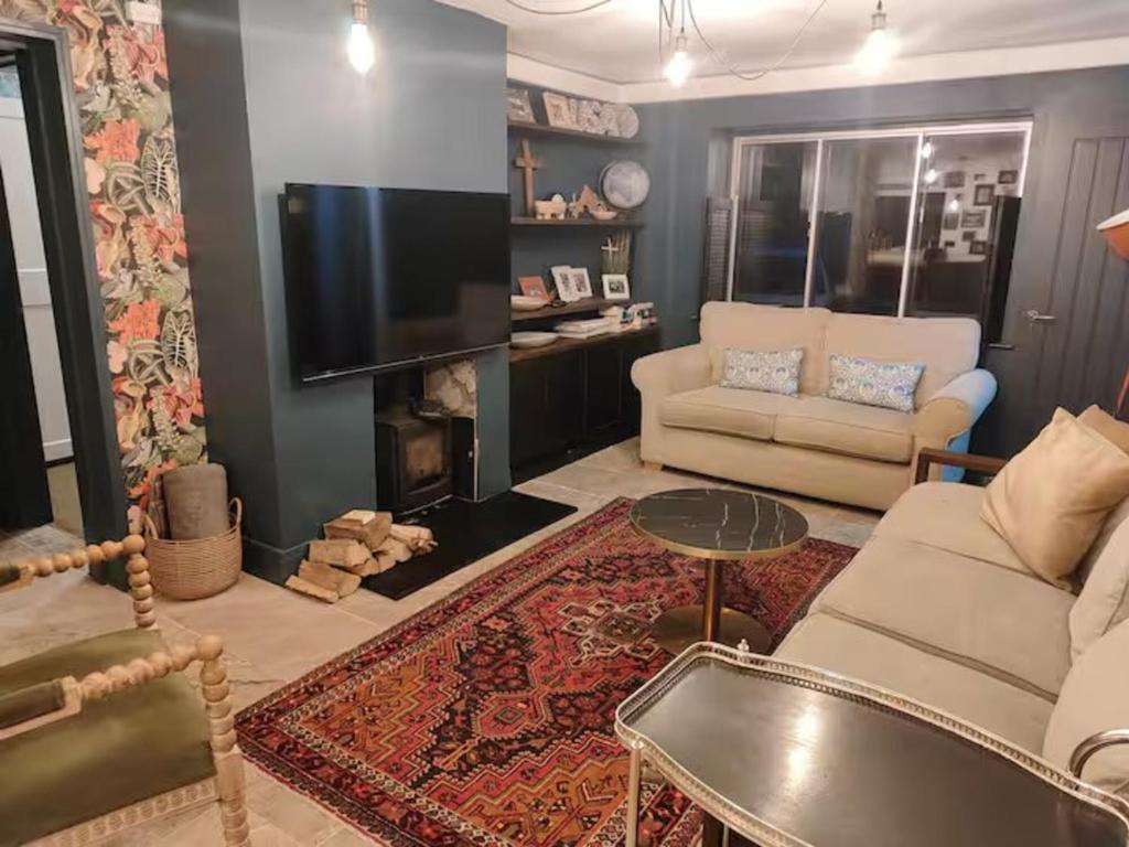 a living room with a couch and a tv at Cotswold Stay in Burford