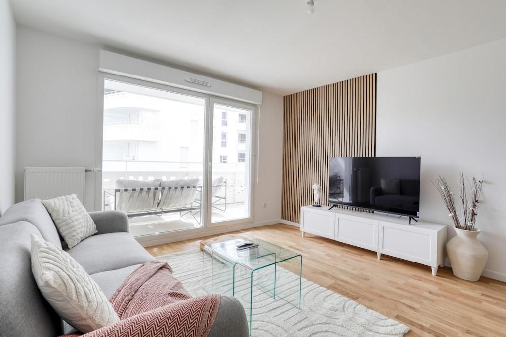 un salon avec un canapé et une télévision dans l'établissement Home Sweet Home, à Bezons