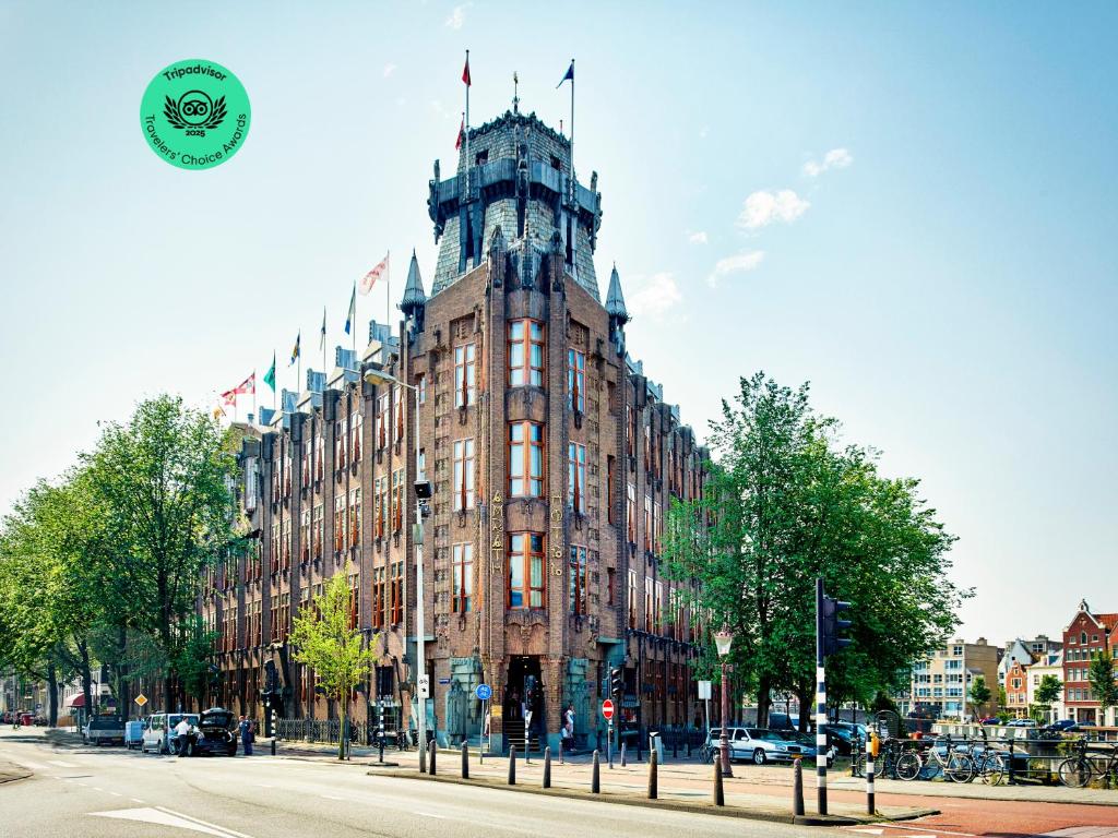 a large building with a clock tower on a street at Grand Hotel Amrâth Amsterdam in Amsterdam