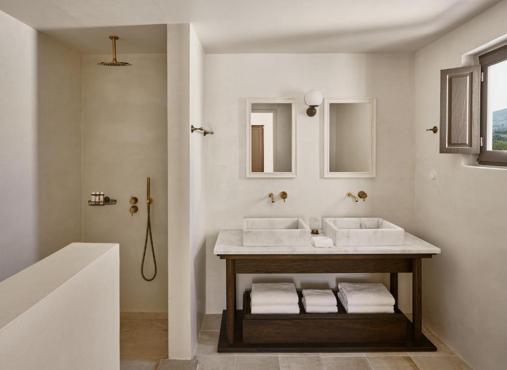 a white bathroom with two sinks and a tub at Parilio, a Member of Design Hotels in Naousa